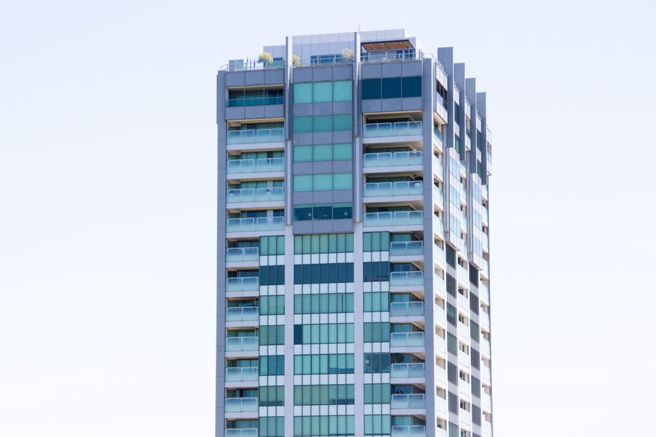 A modern high-rise building with glass windows and balconies in Melbourne, Australia.