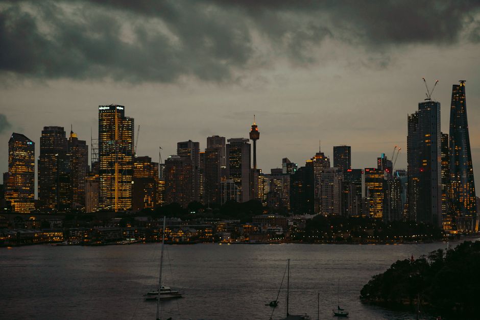 Stunning view of North Sydney's skyline at night with illuminated skyscrapers under dramatic clouds.